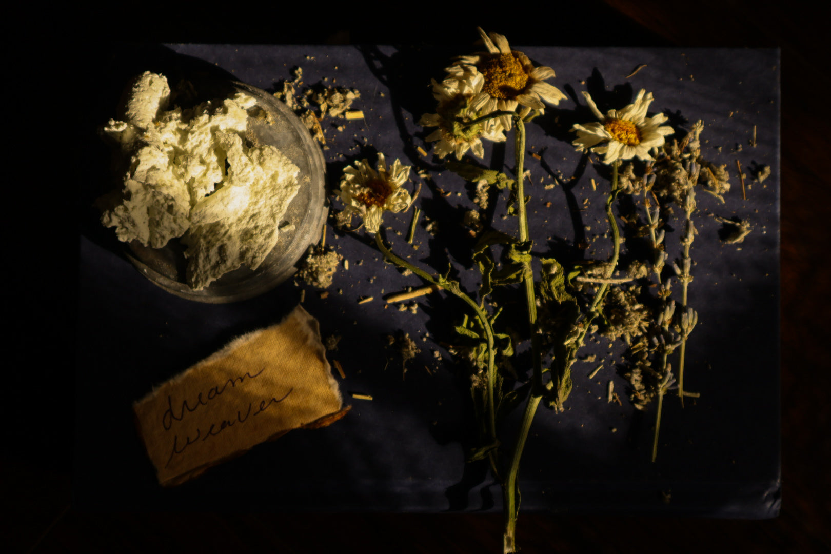Dream Weaver whipped tallow balm with dried chamomile flowers and handwritten label on dark background