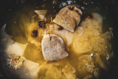 Chamomile and calendula herbal bath bags steeping in golden water