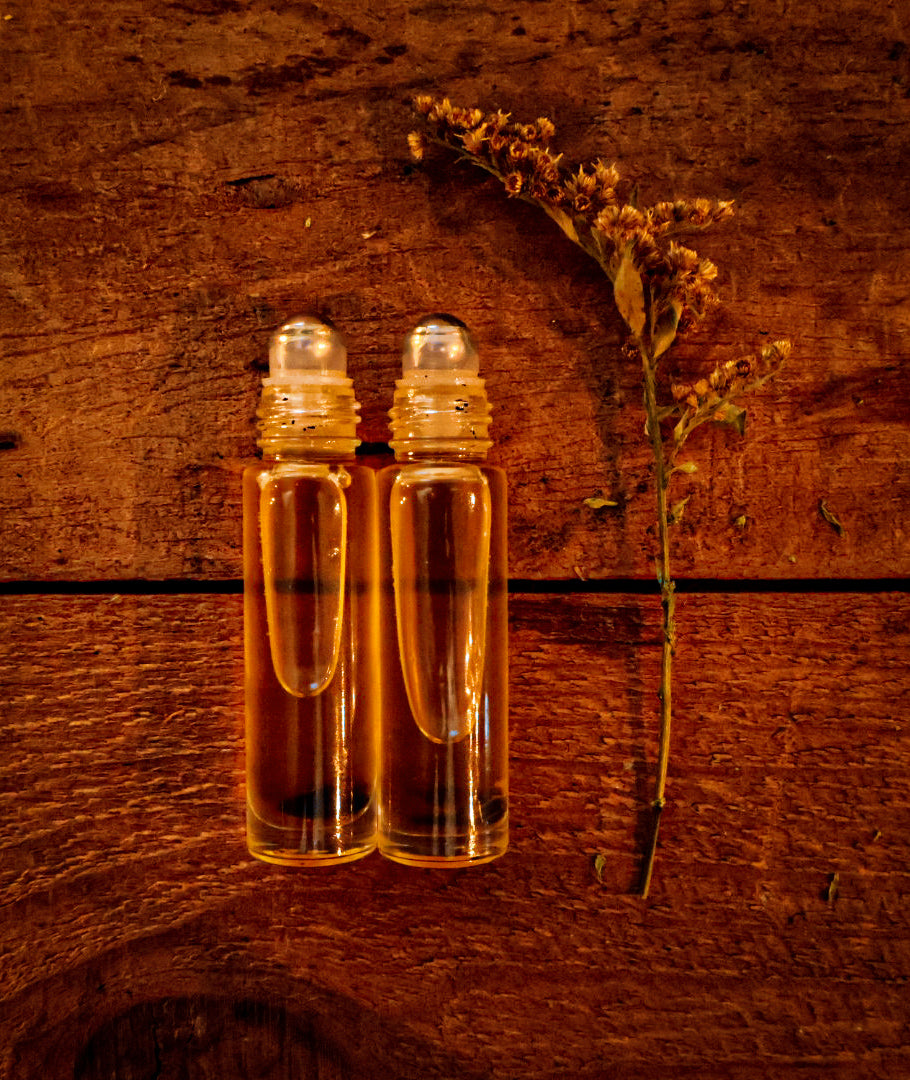 The Gentle Guardian Pocket Oil Roller — roller bottles on warm wood with dried goldenrod