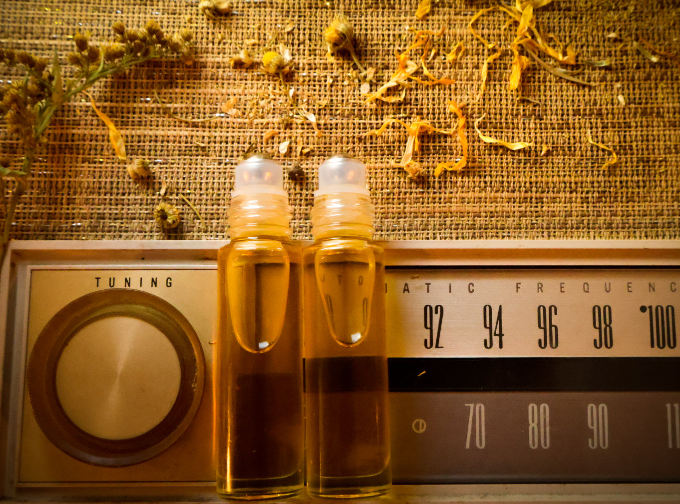 Front Porch Remedy Pocket Oil Roller — roller bottles on a vintage radio with dried botanicals
